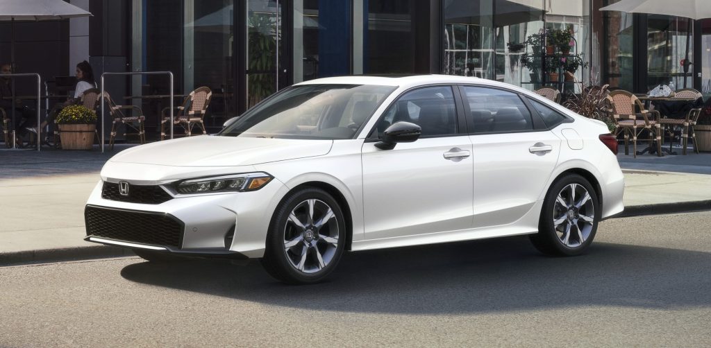 Side view of a white 2025 Honda Civic Sedan Hybrid parked on a city street.